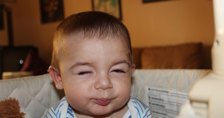 Naklejka premium five months old baby boy in the cot making funny faces