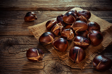 Roasted chestnuts on a sack napkin and wooden background