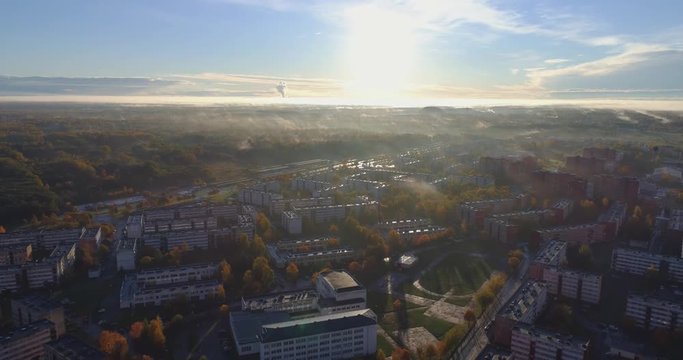 Beautiful Aerial Shot of Misty Sunrise in small town. Colorful clouds, fog above the city. Camera tit up.