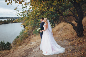 happy newlyweds are walking by the lake and admiring the water.