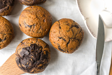 chocolate vanilla muffins on the table, beside the butter-dish and knife, top view