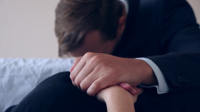 funeral, sadness and mourning concept - a sad man talking and crying next to the coffin. 4k,