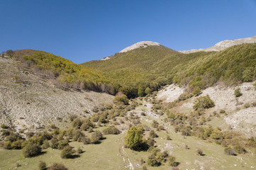 Aerial view of a beautiful mountain landscape, with hills full of green trees and a  small valley. Autumn season in Italy.