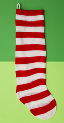 Fototapeta na wymiar Red and White Striped Stocking on a Duel Green Background