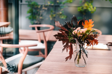 Autumn bouquet in a glass vase on wooden table. Holiday season, wedding decor concept. 