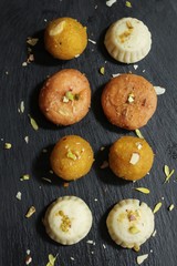 Diwali sweets -  Laddu Peda and Balushahi on dark slate with copy space