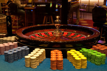 Golden Casino theme. High contrast image of casino roulette, poker game, dice game, poker chips on a gaming table.