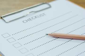 Checklist concept - checklist, paper and a pen with checklist word on wooden table