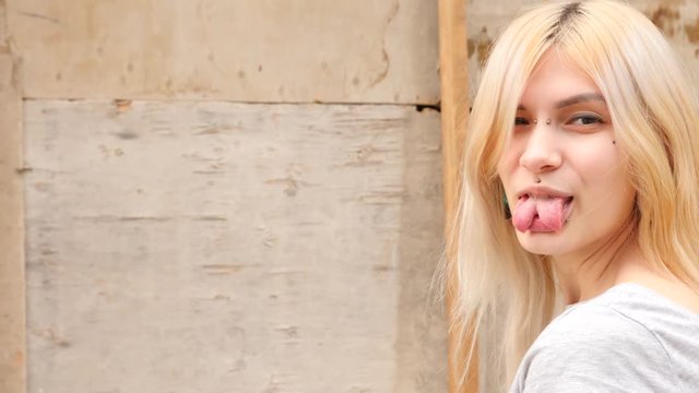 bodymification. a girl with a split tongue turns to the camera and shows her tongue. 4k, slow-motion, copy space 