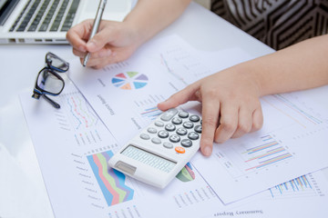 close up woman using calculator on paper graph data with doing finance at office.