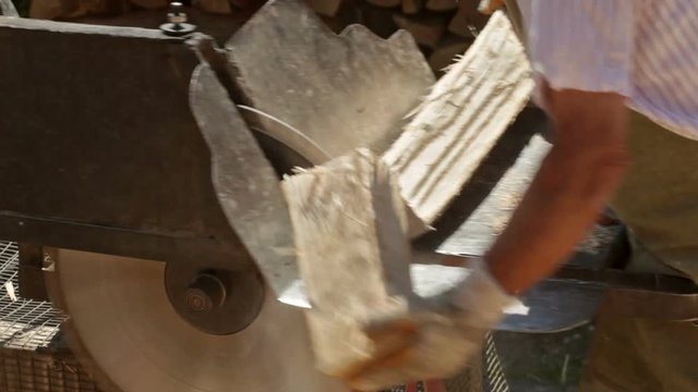 Male workers cutting firewood logs with circular saw powered by tractor engine - static camera, closeup