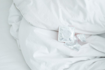 Cropped shot view of condoms on the bed.