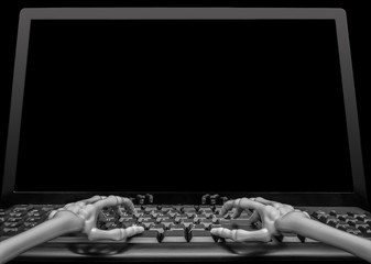 View of two skeleton hands typing on a keyboard in front of a blank computer screen ready for someone to fill with graphics or text.