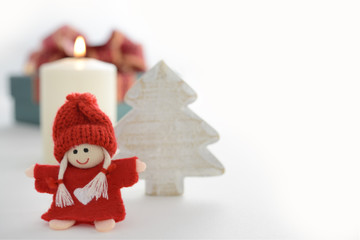 Festive Christmas decoration with tiny doll, wooden Christmas tree and candle with copyspace on white