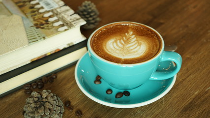 Hot coffee with textbook latte mocha espresso cappuccino with heart shape foam in green cup coffee shop wooden tabvle and coffee bean