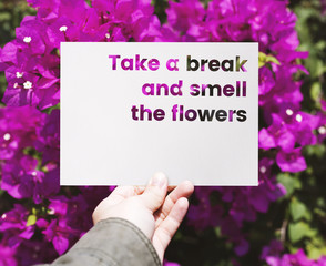 Hand holding paper with take a break and smell the flowers word cut out