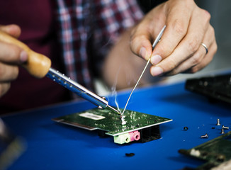 Hands soldering tin on electronics circuit board