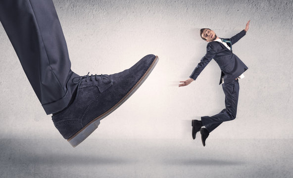 Small businessman kicked by big shoe