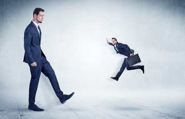 Big businessman kicking small businessman