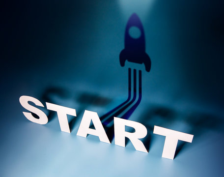 Startup Concept, Start Text standing in Front with Rocket Shadow shape at the Wall