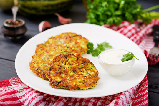 Zucchini pancakes with parsley on a wooden table.