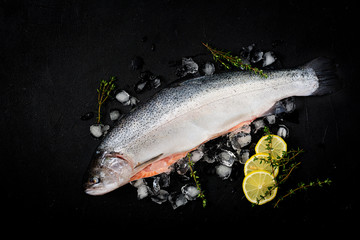 Fresh raw salmon red fish with ice on a dark background. Flat lay. Top view