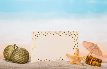 Blank card, an umbrella, Christmas balls and gifts, starfish in the sand