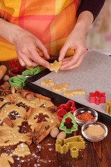 Woman lays biscuits for baking on baking tray, on table