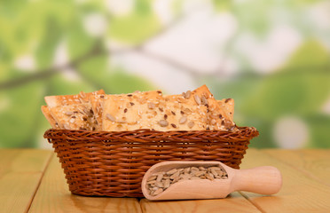 Fototapeta na wymiar Basket with crispy biscuits and wooden scoop with fried sunflower seeds on an abstract green background.