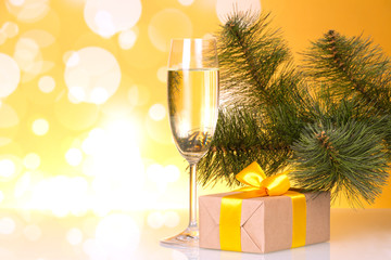 Fouger with champagne and box with gift on yellow sparkling background