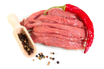 Pieces of raw beef, spicy red pepper and scoop with different round peppers isolated on white.