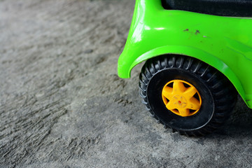 green tpy car with black wheels on rough and dirty cement