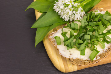 bread and butter with chopped wild garlic on wooden board