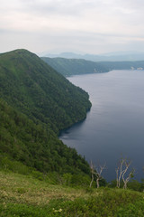 Obraz na płótnie Canvas Green slopes surrounding the beautiful and deep blue Lake Mashu, Hokkaido, Japan