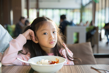 Little asian girl feeling bore the food with the rice and tomato sauce