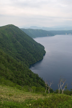 Green slopes surrounding the beautiful and deep blue Lake Mashu, Hokkaido, Japan