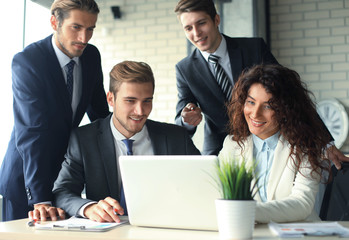 Startup business team on meeting in modern bright office interior and working on laptop.