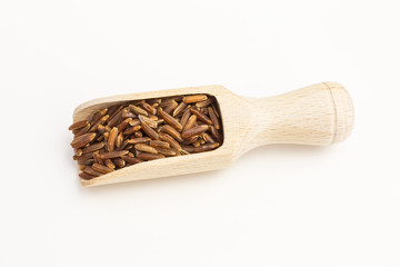 red rice grains on wooden scoop