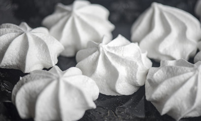 Close-up picture of meringues on a black plate, food background.