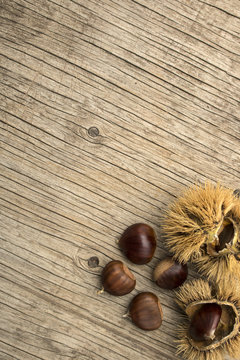Sfondo autunnale con castagne e ricci di castagno su sfondo di legno d'epoca