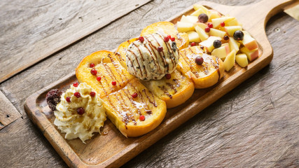 Honey Toast and ice cream with mixed fruit on a wooden table.