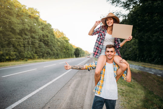 Young hitchhiking couple with empty cardboard
