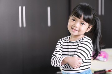 Asian children cute or kid girl feel business child with cross one's arm and smile white teeth with confidence after dressed up in the room at home office with space