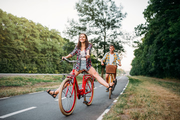 Obraz premium Young man and woman walking on retro bikes