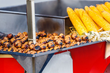 Boiled yellow corn and roasted chestnuts close up, street food concept