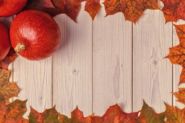 Autumn background with colored leaves and pumpkins on wooden background.