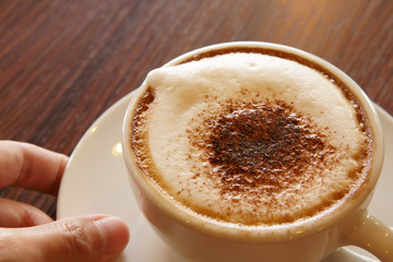 serve fresh hot cappuccino coffee in white cup on wood table in the morning for breakfast drink before work on warm white and nature light at coffee shop or office