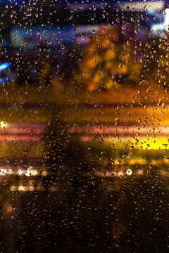 Texture of a drop of rain on a glass in the background of a night city © shintartanya