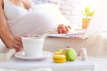 Woman using laptop and having breakfast in bed