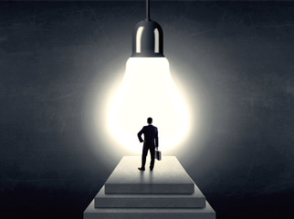 Man standing on a step in front of a huge light bulb